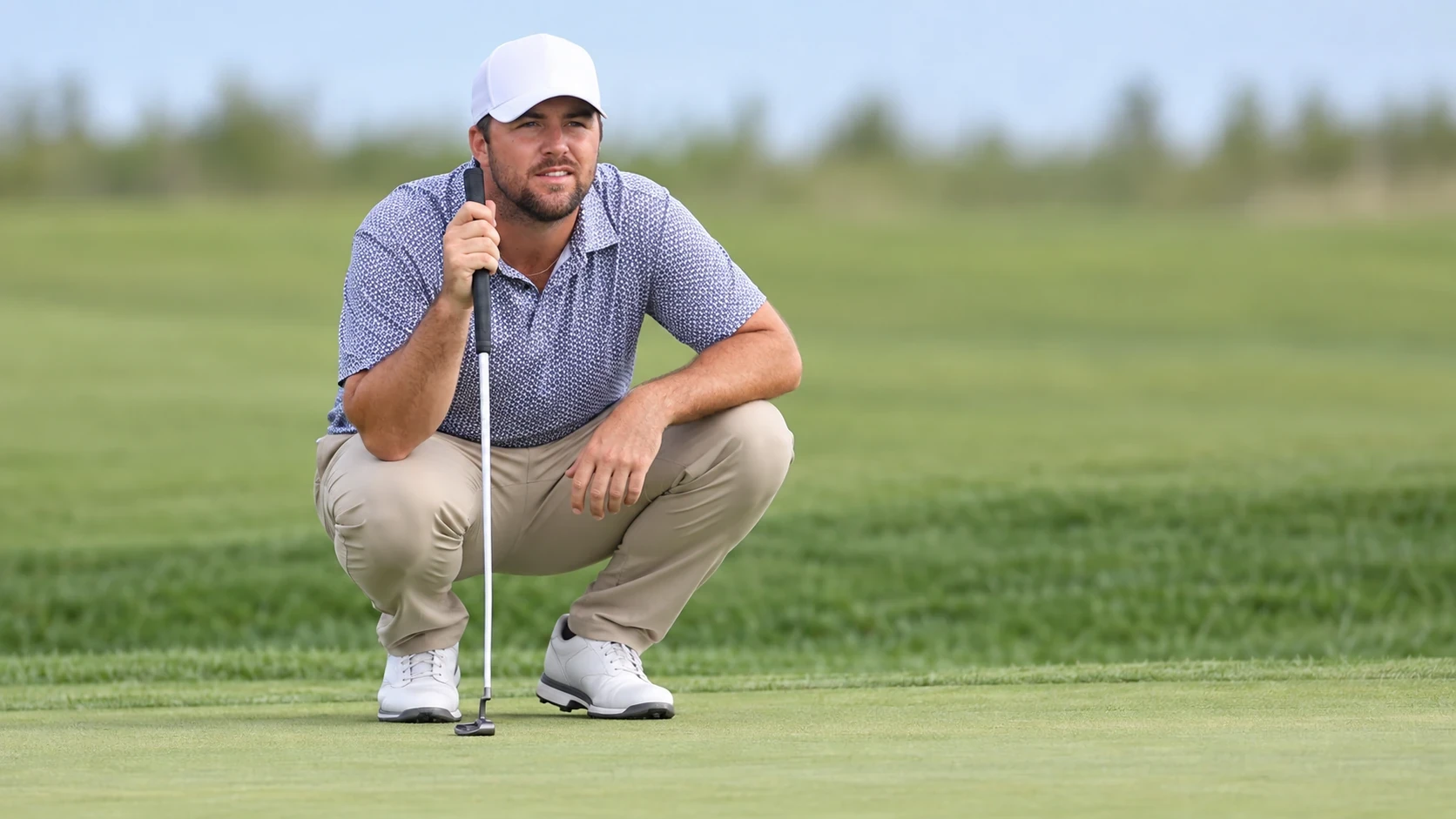 Chris Gotterup crouching to read a putt on the green
