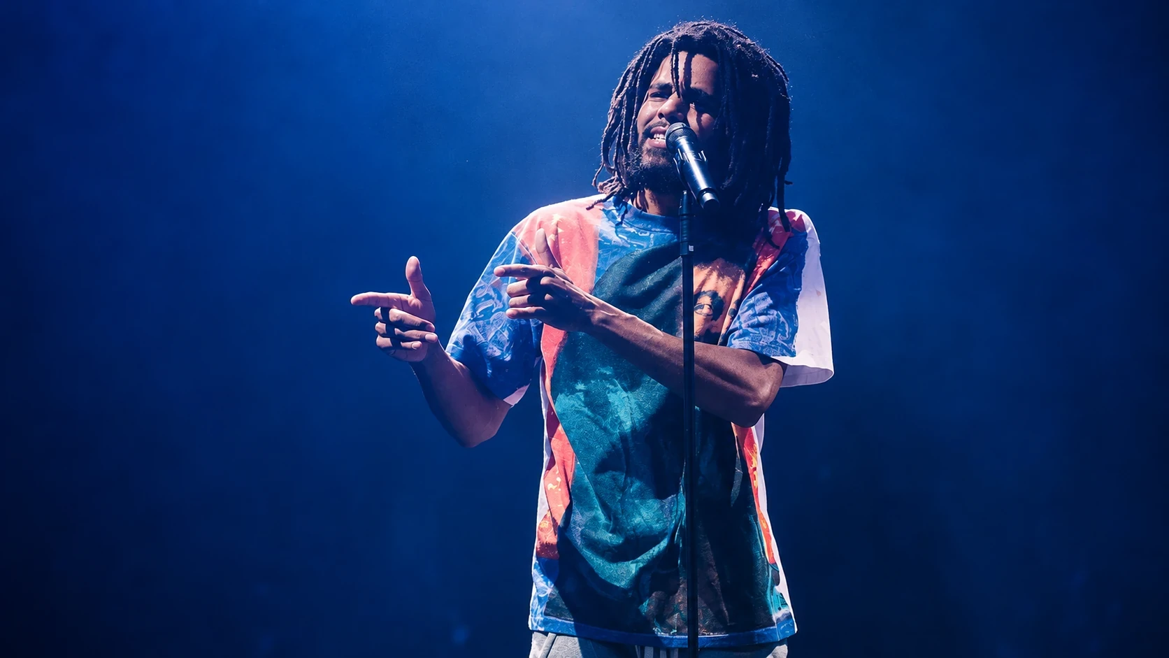J. Cole performing on stage under blue lights